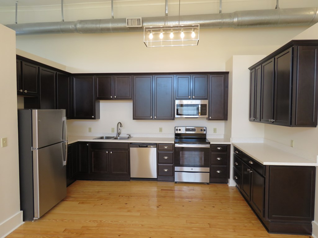 an empty kitchen with black cabinets and stainless steel appliances