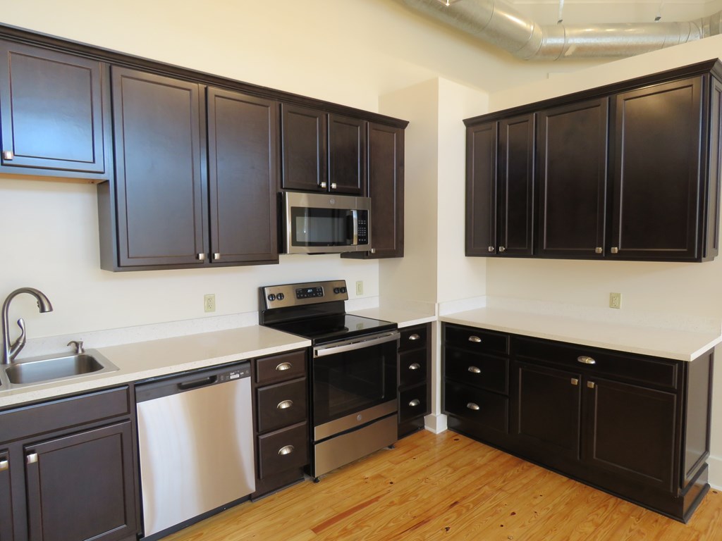 an empty kitchen with black cabinets and stainless steel appliances