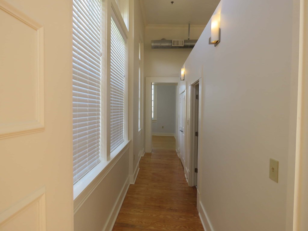 a hallway with white walls and windows and a wood floor