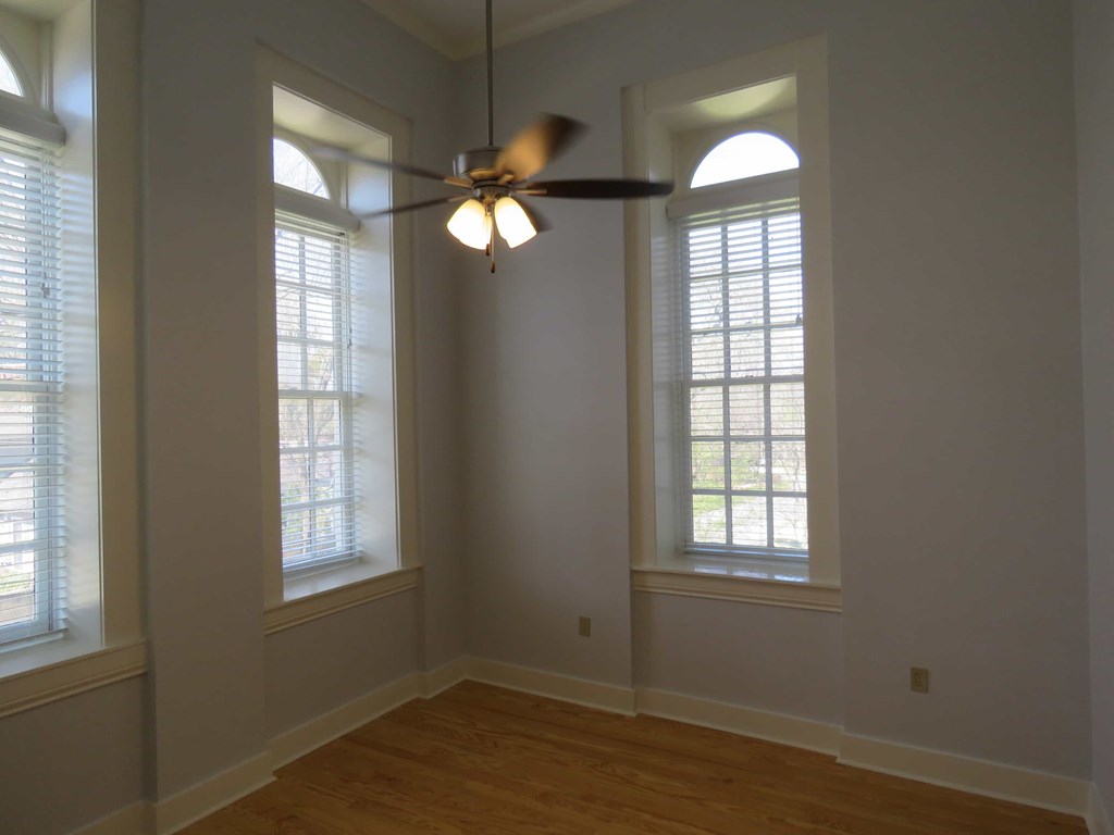 a living room with two windows and a ceiling fan