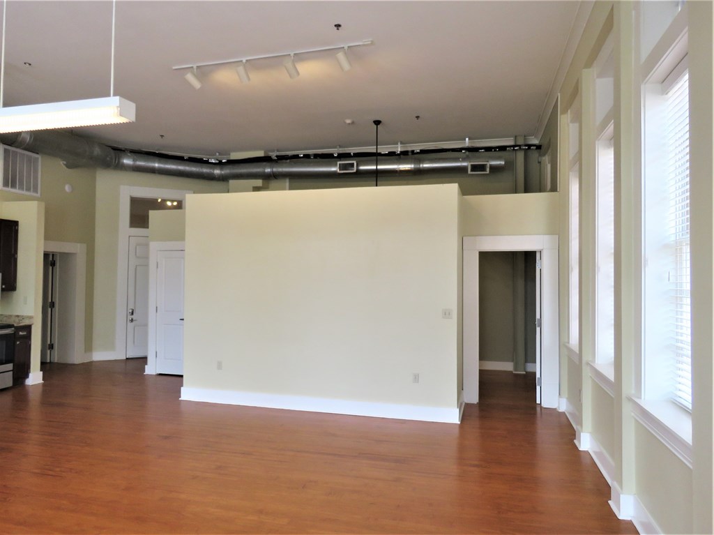 an empty living room with a large white wall and wood floors