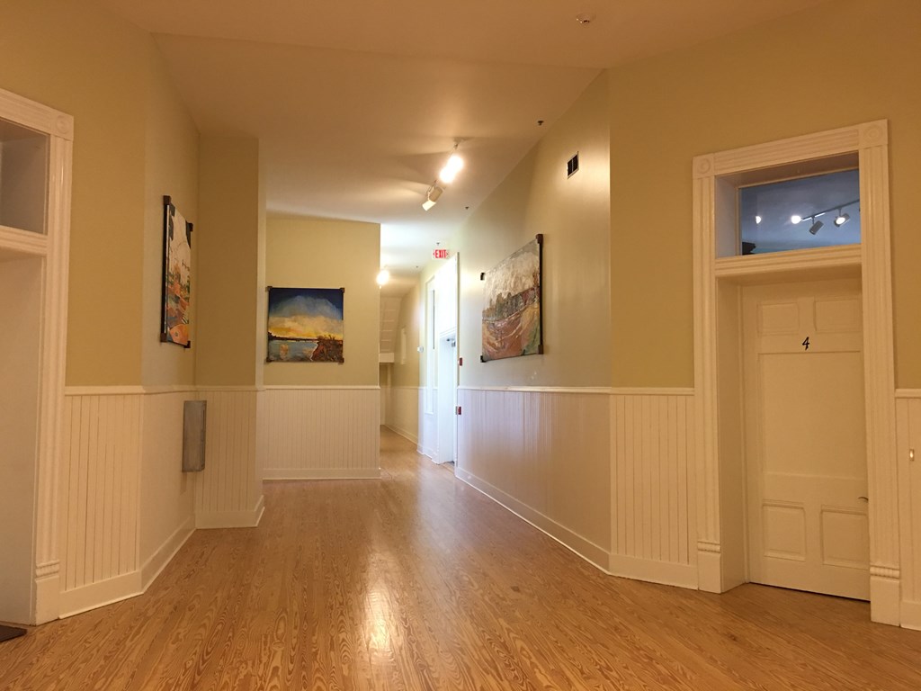 a large room with wood floors and paintings on the wall