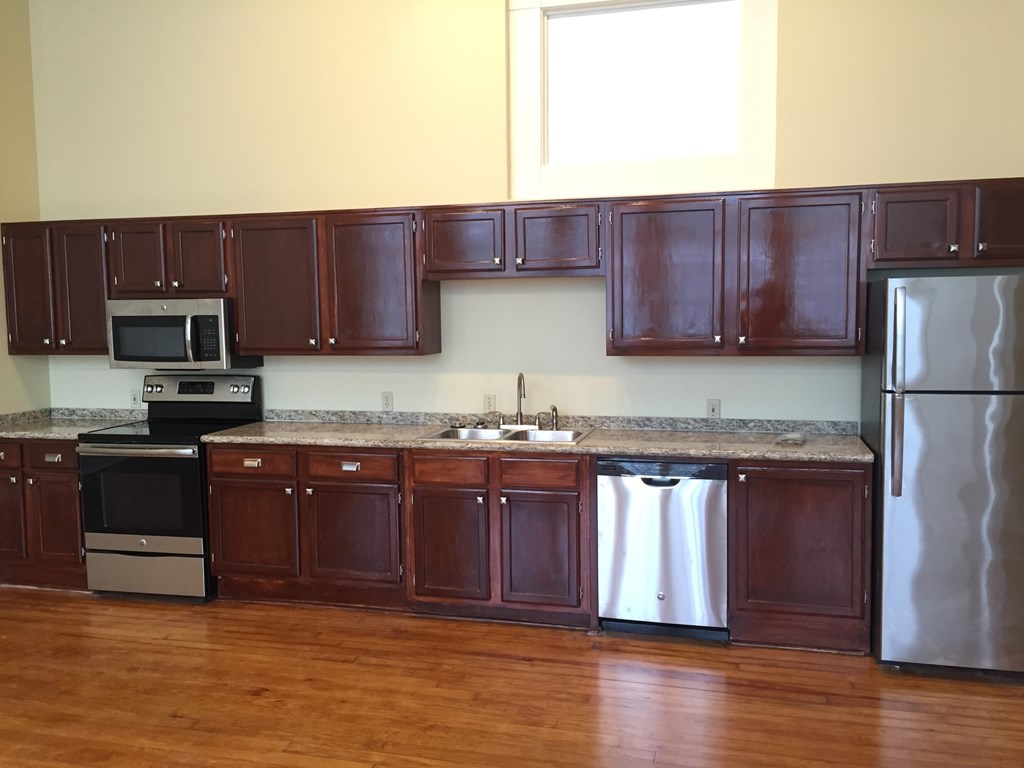 an empty kitchen with wooden cabinets and stainless steel appliances