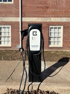 a gas pump sitting on a sidewalk in front of a building