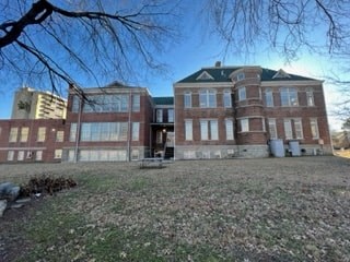 a large brick school building with a grass field in front of it