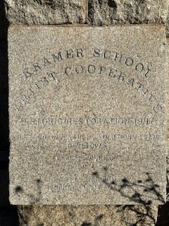 a tombstone with the name of a school on a brick wall