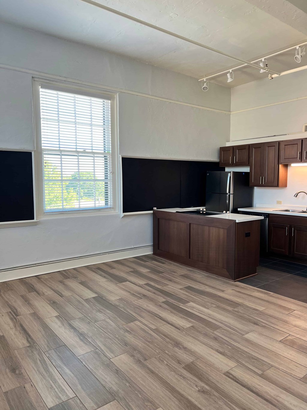 an empty kitchen with wooden floors and a window