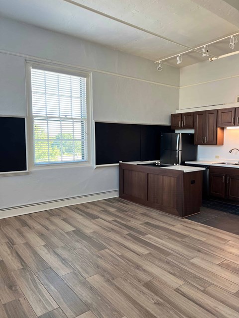 an empty kitchen with wooden floors and a window