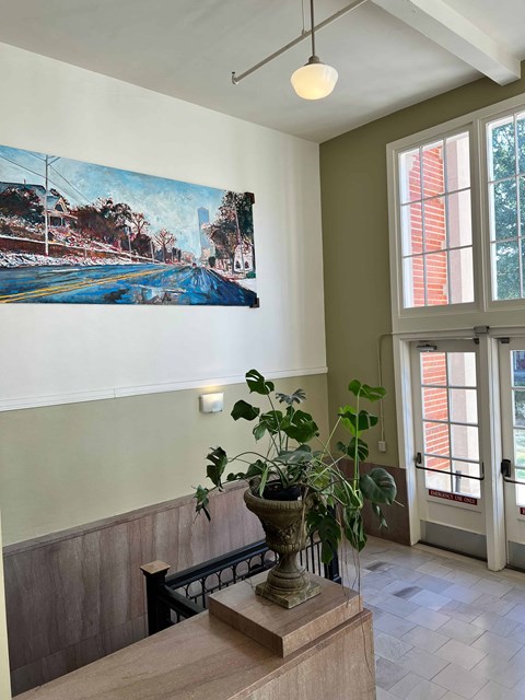 a potted plant on a table in a room with a painting on the wall
