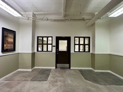 an empty room with a door and paintings on the wall