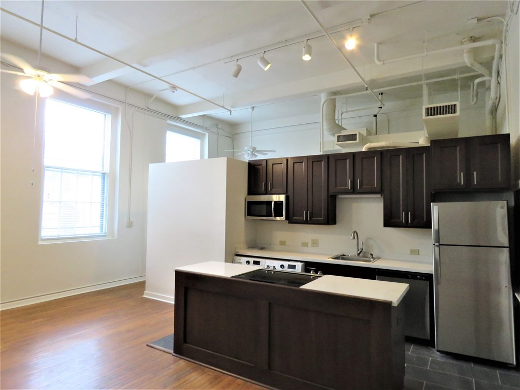 an empty kitchen with black and white cabinets and stainless steel appliances