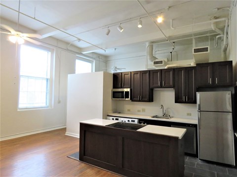 an empty kitchen with black and white cabinets and stainless steel appliances