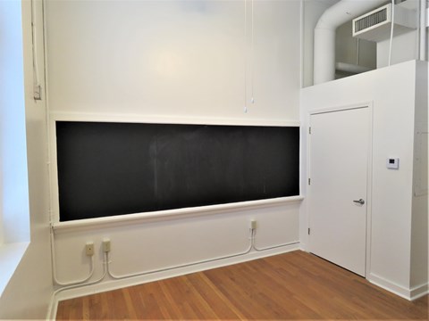 an empty room with a blackboard on the wall and a door