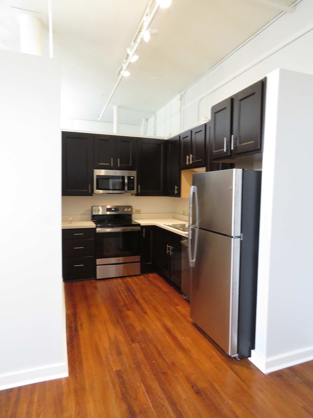 a kitchen with black cabinets and a stainless steel refrigerator