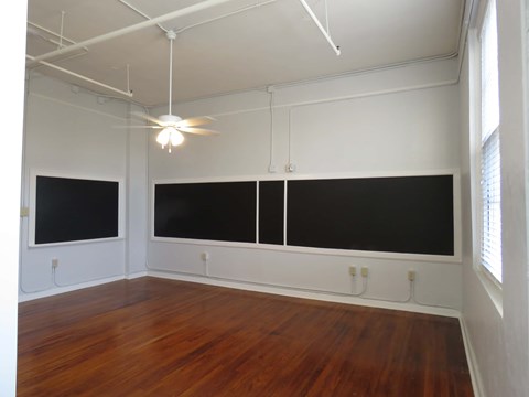 an empty room with two screens on the wall and a ceiling fan