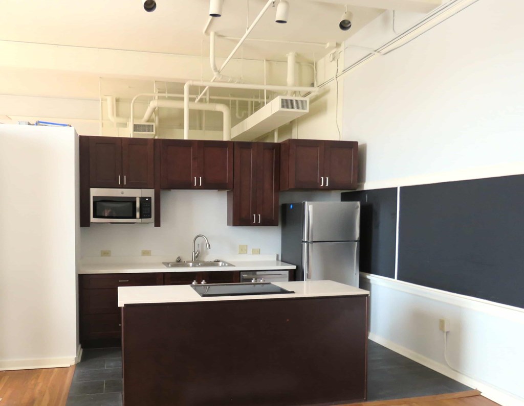 an empty kitchen with dark cabinets and white counter tops