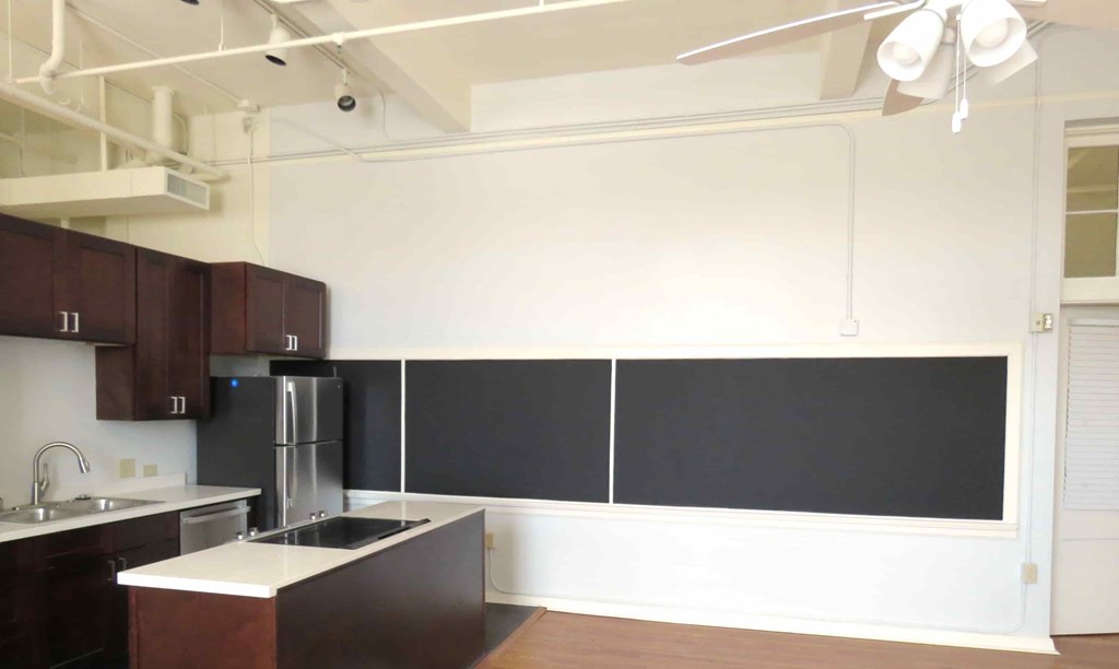 an empty kitchen with black and white walls and stainless steel appliances
