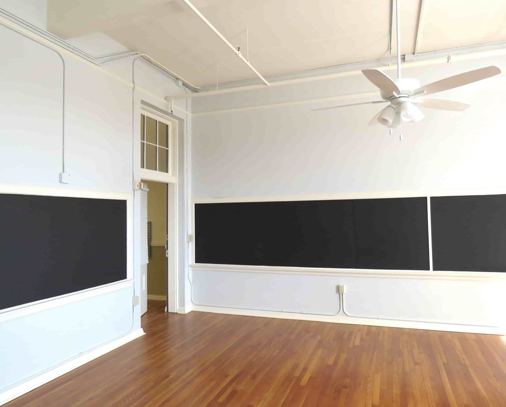 a room with a blackboard on the wall and a ceiling fan