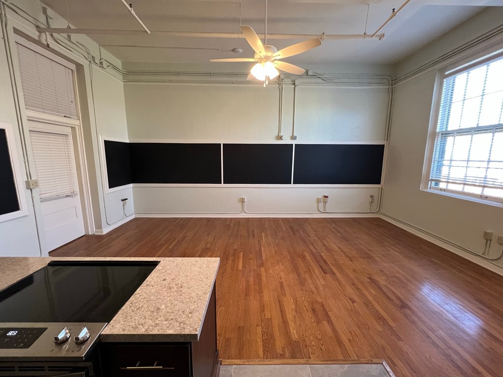an empty living room with a wood floor and a ceiling fan