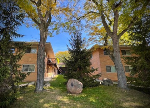 A large rock sits in the grass in front of a building.