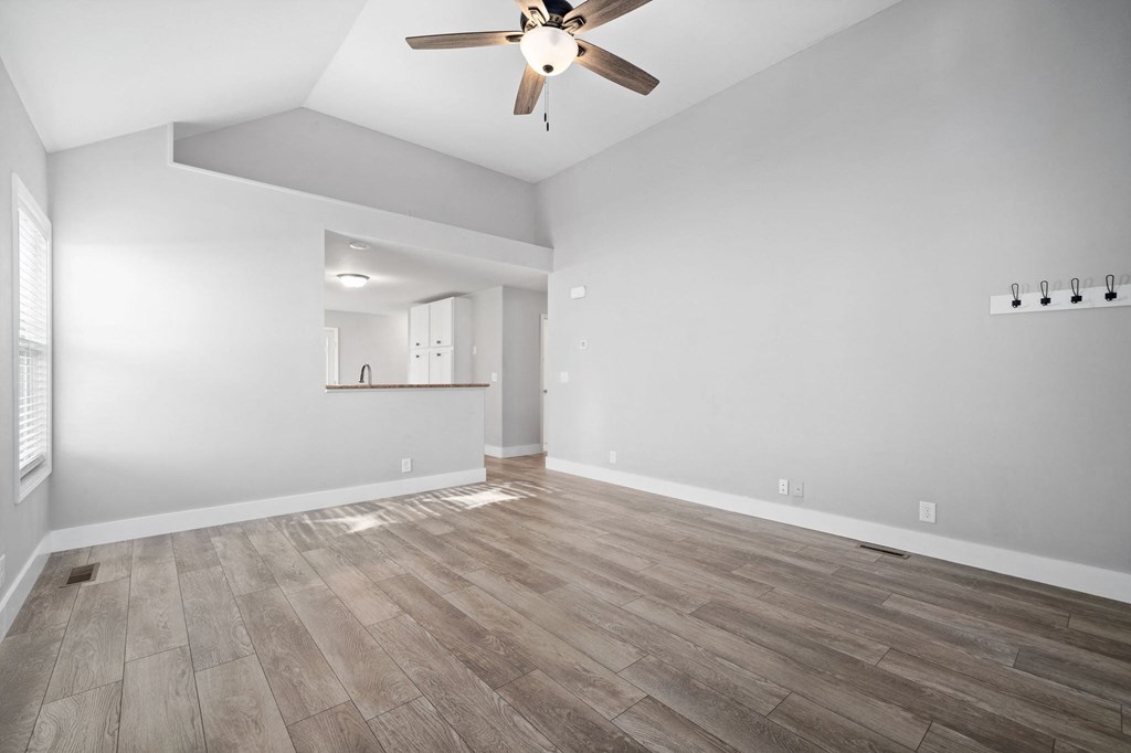 the living room is empty and has a ceiling fan