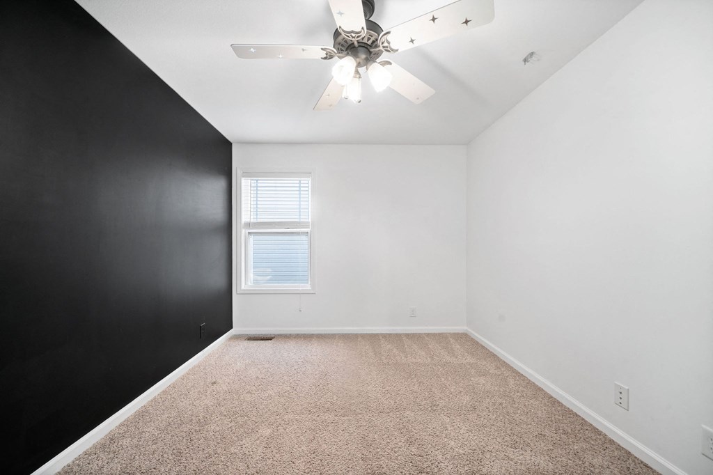 an empty room with black and white walls and a ceiling fan