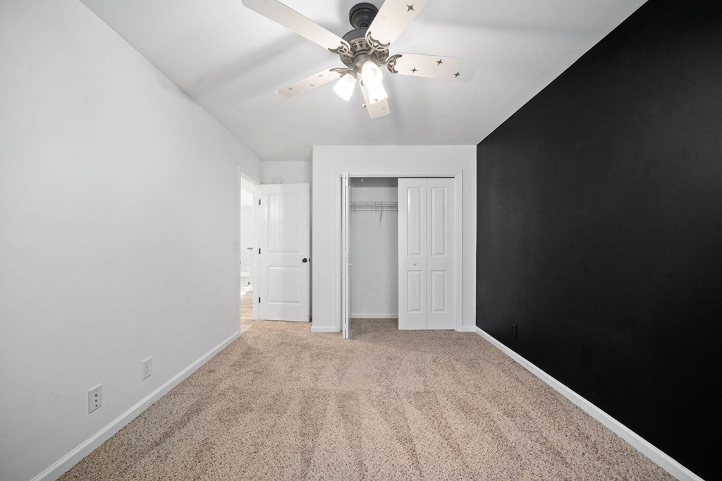 an empty bedroom with black and white walls and a ceiling fan