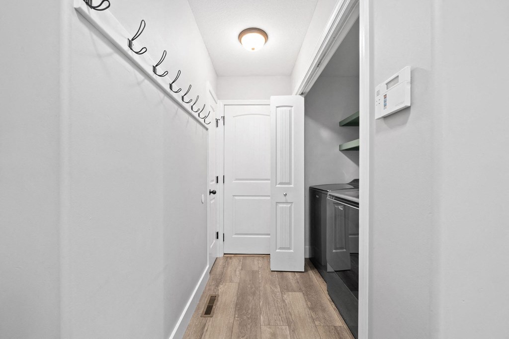 a hallway with white walls and a white door and a laundry room