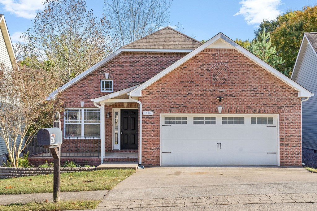 the front of a brick house with a white garage door