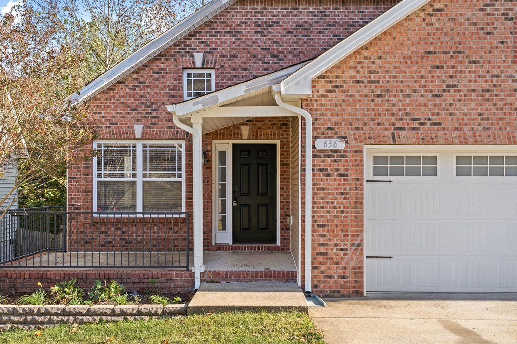 a brick house with a black door and a white garage door