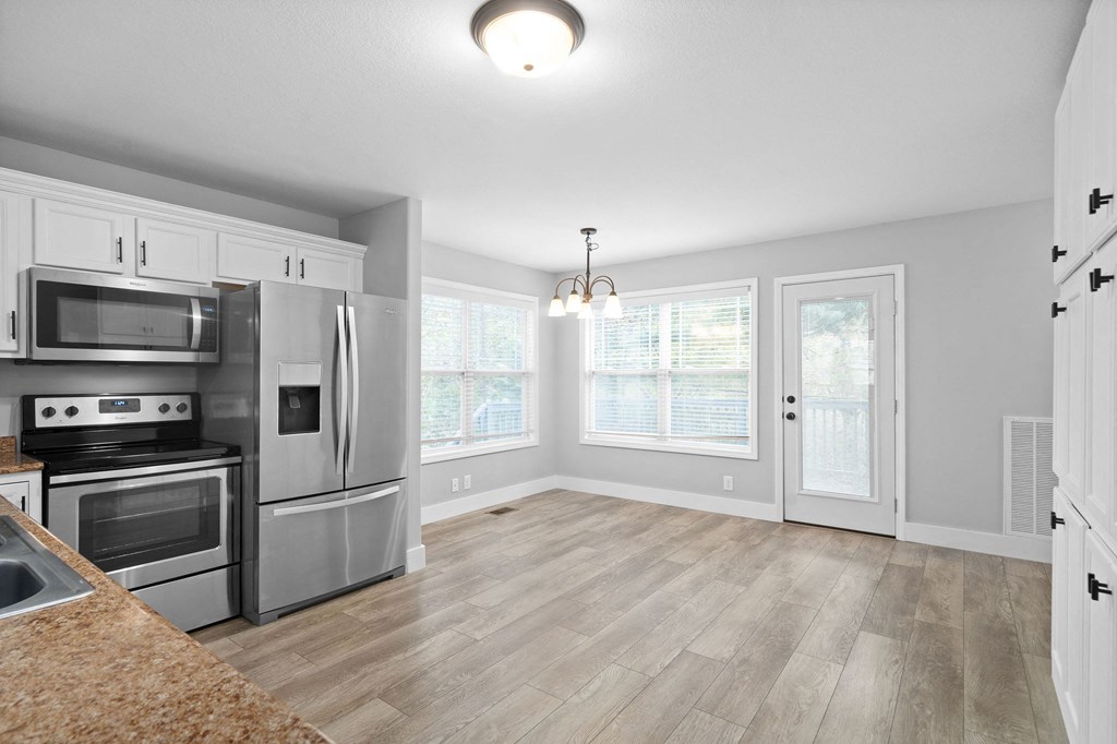 an empty kitchen with stainless steel appliances and white cabinets