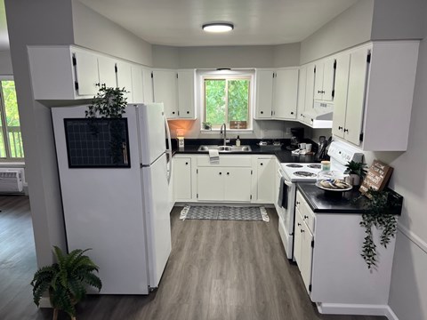 A kitchen with white cabinets and a black countertop.