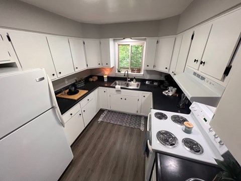 A kitchen with white cabinets and black countertops.