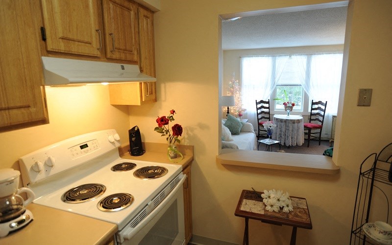 a kitchen with a stove and a window and a dining room
