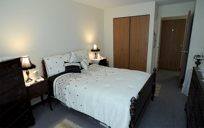 a bedroom with a bed and two dressers and a closet