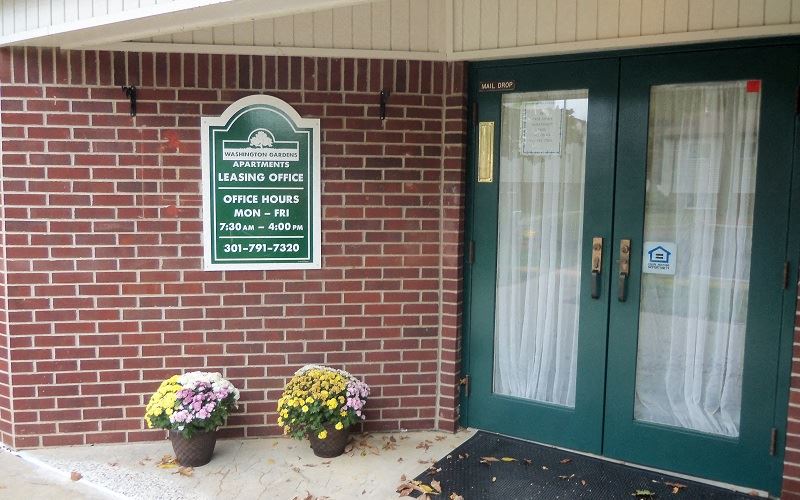 a brick building with green doors and a sign for leasing office