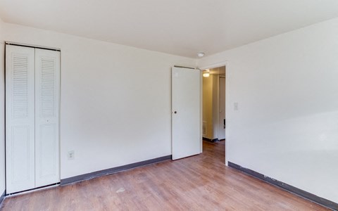the living room of a house with white walls and a wood floor