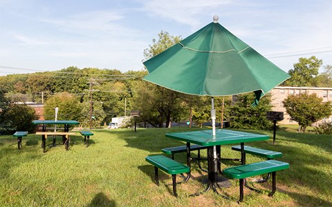 a group of picnic tables with an umbrella in a park