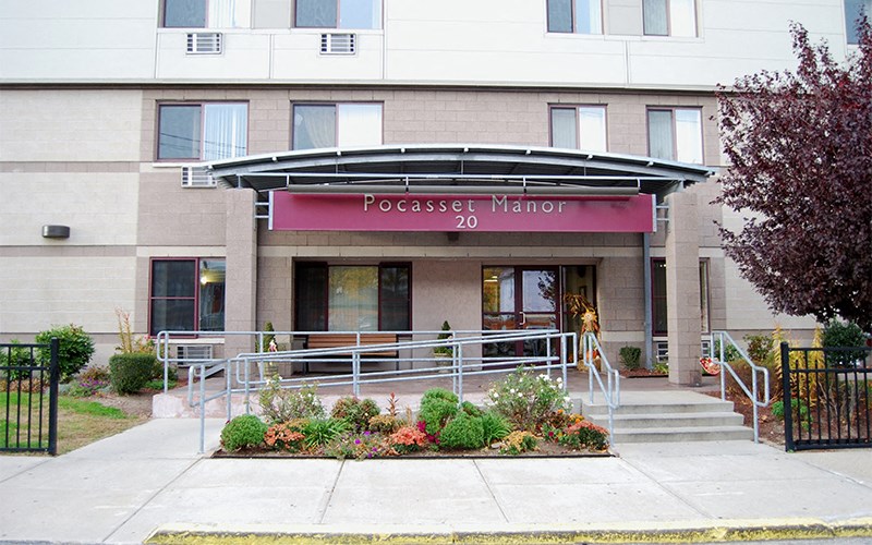 the front of a building with stairs and a red sign