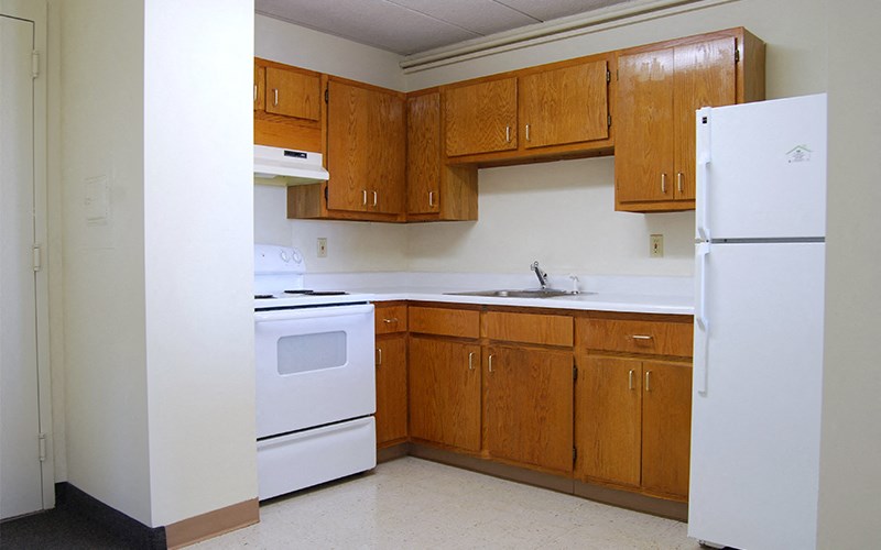 an empty kitchen with white appliances and wooden cabinets