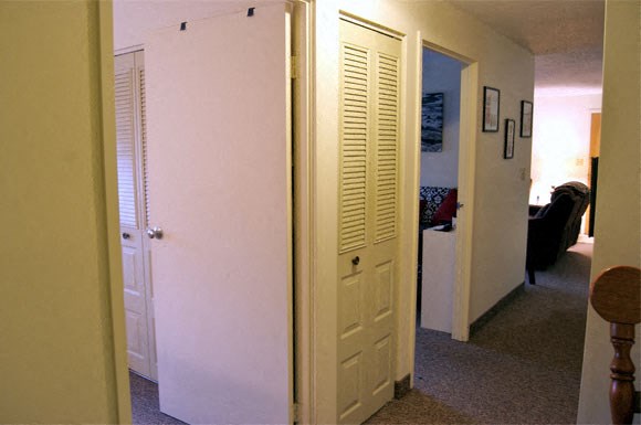 a hallway with a white door and a living room