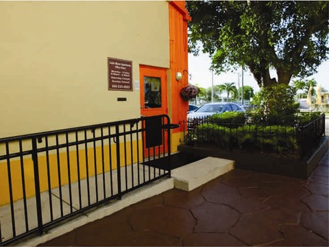 the entrance to a building with a black railing and a tree