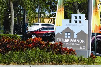 a sign for the culver manor hotel with flags in front of the parking