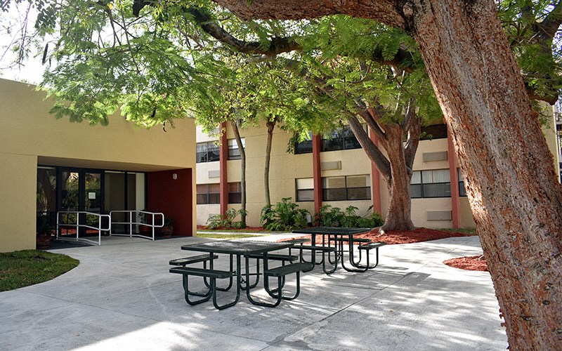 a courtyard with tables and benches in front of a building