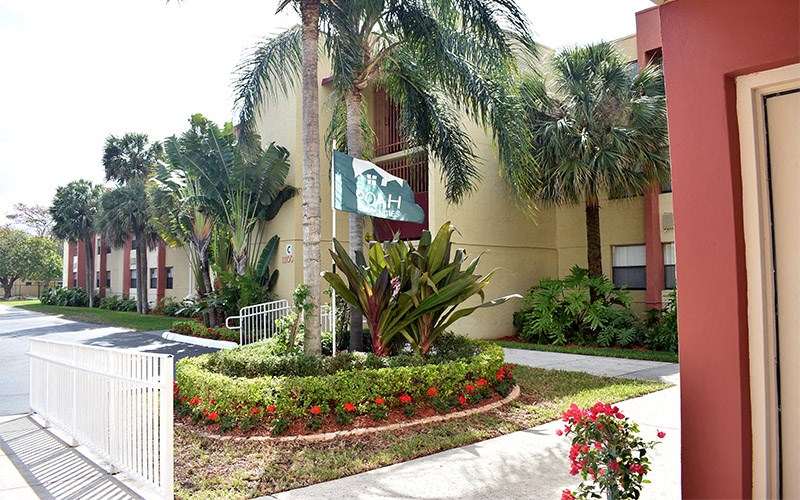 a building with palm trees and flowers in front of it