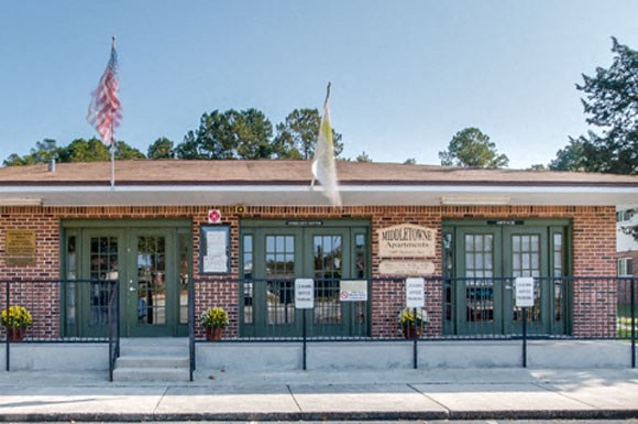 a brick building with two flags on the sidewalk
