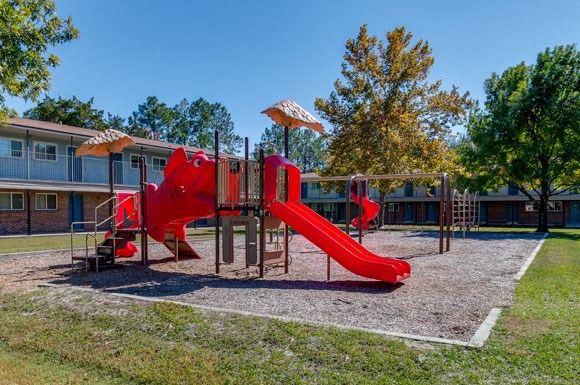 a playground with a red slide in front of a building