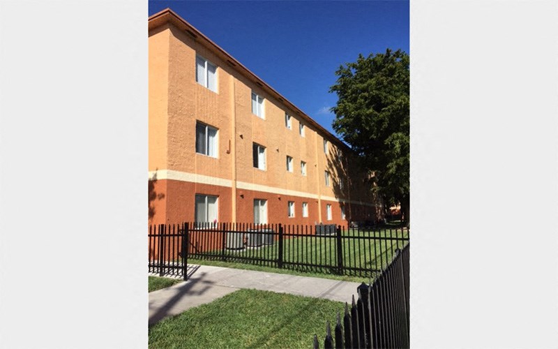 the side of a brick building with a yard and a fence