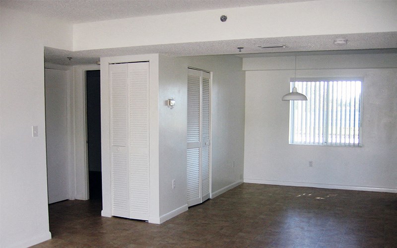 an empty living room with white walls and a window
