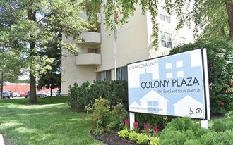 a sign for colony plaza in front of an apartment building